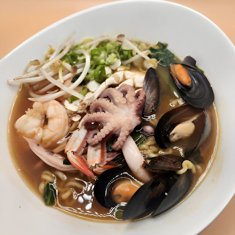 A bowl of Korean seafood ramen with mussels, shrimp, octopus, and bean sprouts.